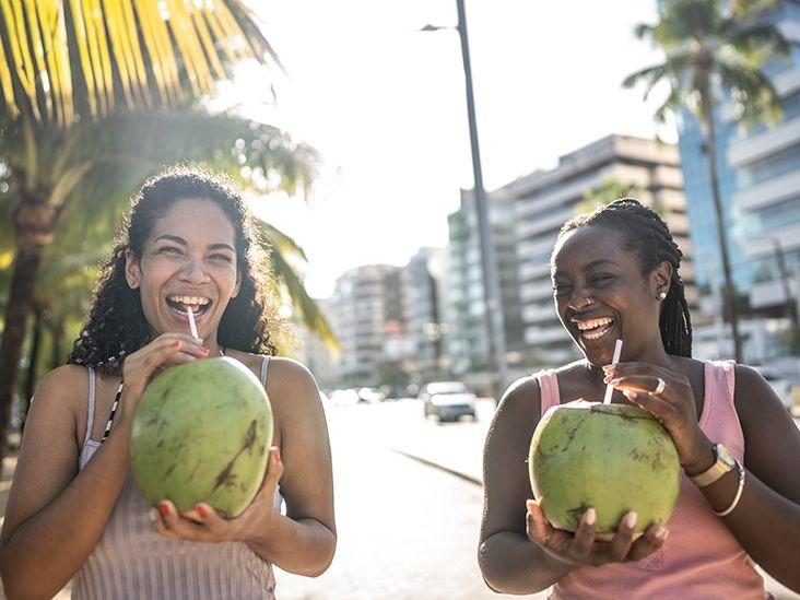 two-women-friends-smiling-laughing-drinking-coconut-water-732x549-thumbnail